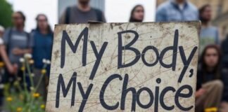 Why Reproductive Justice Is More Than Just Healthcare Weathered "My Body, My Choice" sign with muddy sneakers, blurry crowd, wildflowers.