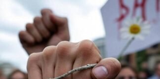Fighting for Choice: The Women Leading the Movement Gritty protest scene, woman's fist with worn bracelet, dripping sign, daisy in megaphone.