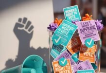 Are Women Still Being Silenced at the Ballot Box? A ballot box overflowing with suffrage flyers, a megaphone, and checkmark confetti.